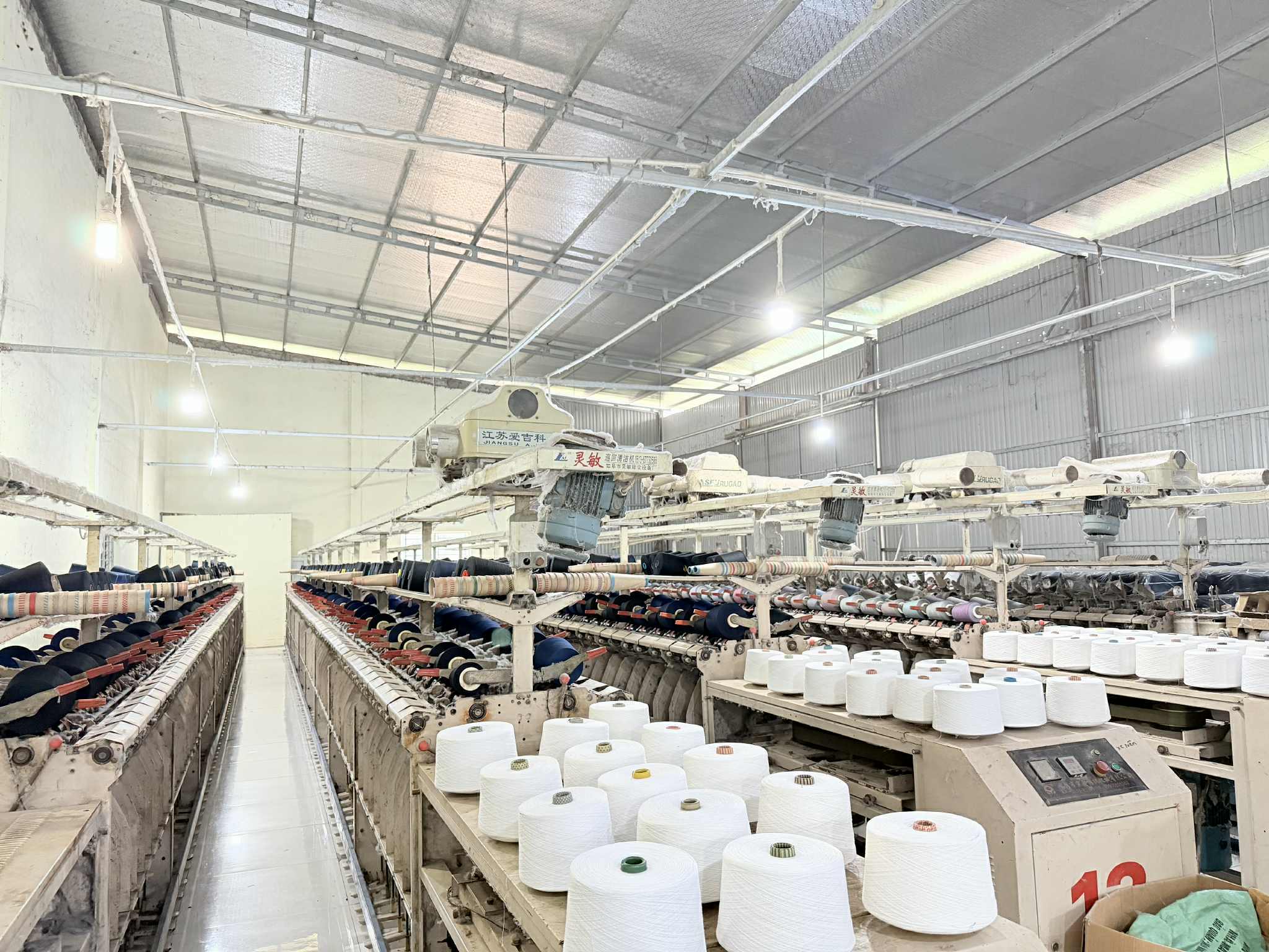 Industrial textile machines with rows of white yarn spools at Son Ha Textile