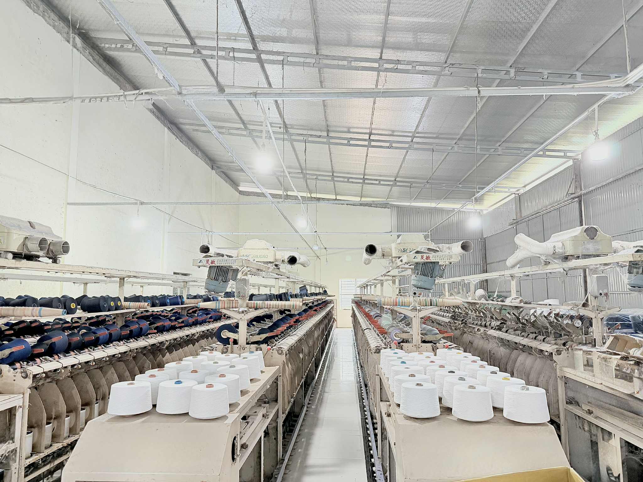Rows of textile machinery and yarn inside the Son Ha Textile factory