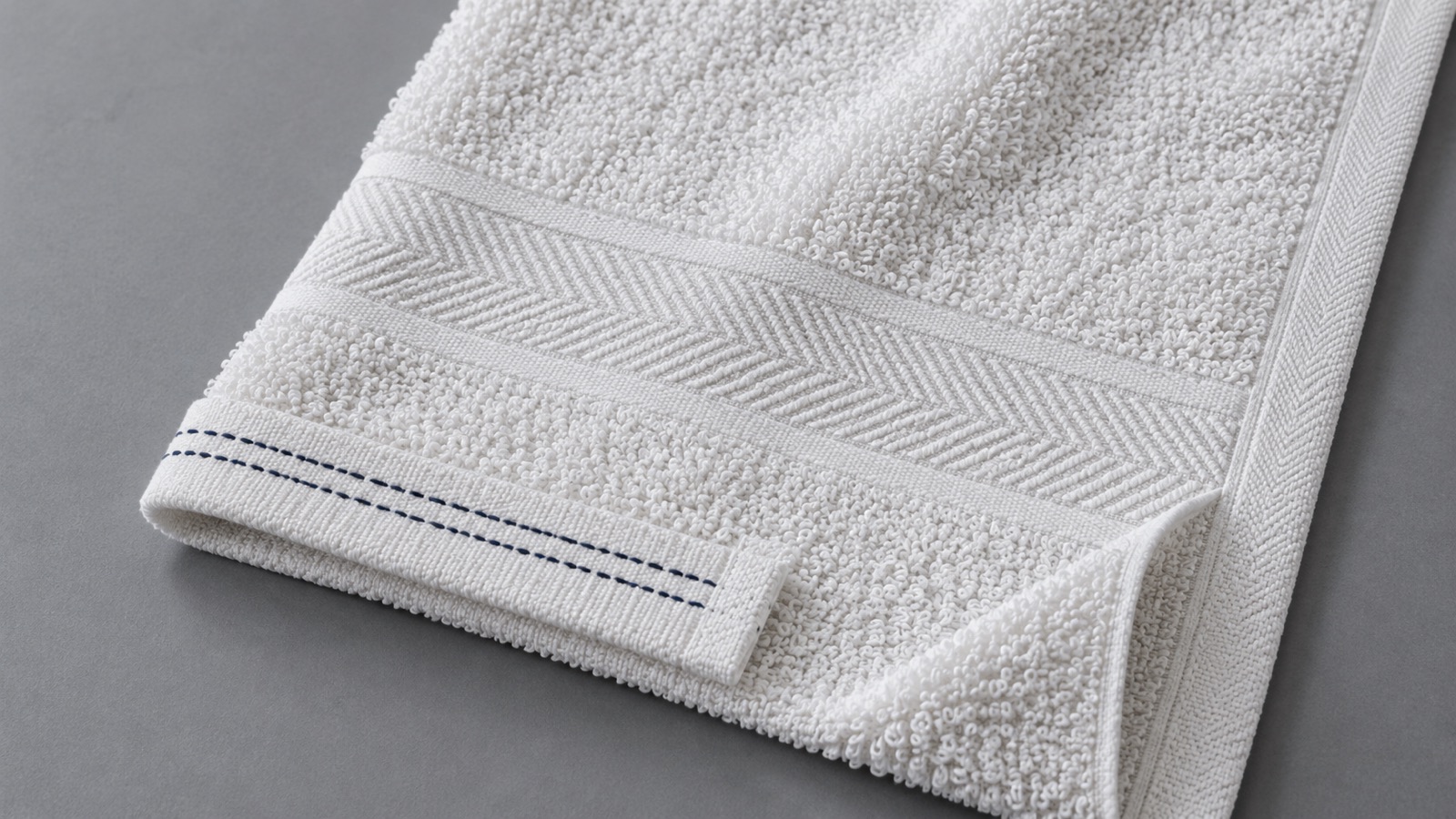 White terry towel showing a flat woven border, folded stitched end hem and compact side selvage